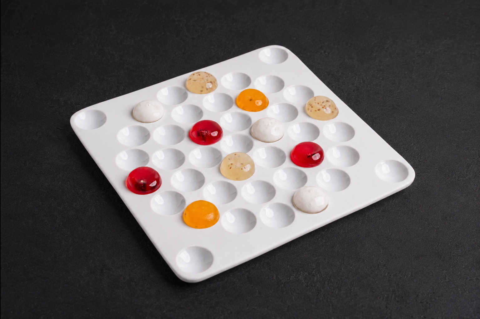 A bespoke white tasting platter arranged with jewel-toned culinary compositions