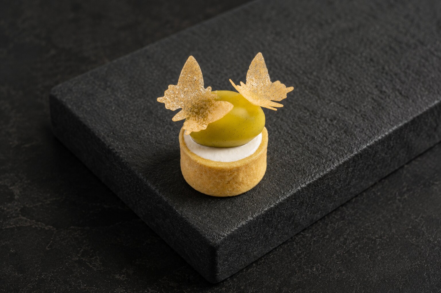 Green dome tart finished with two delicate butterfly garnishes